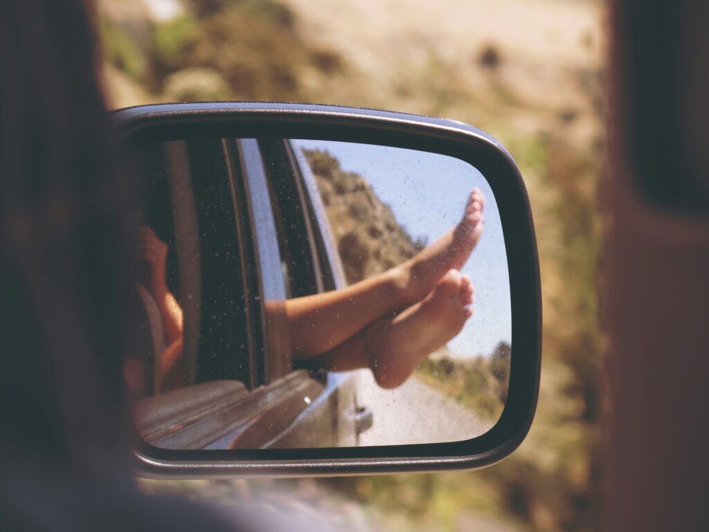 Child's bare feet propped out the car window on a summer road trip