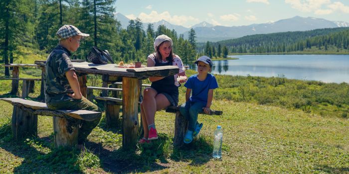 Mom and kids enjoying a quiet picnic lunch beside a lake