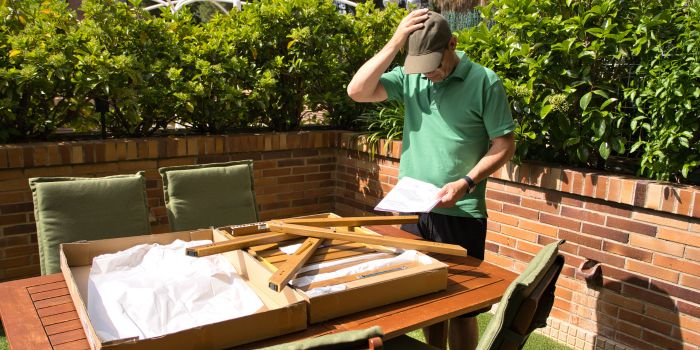 Frustrated homeowner assembling flat-pack patio furniture in the backyard