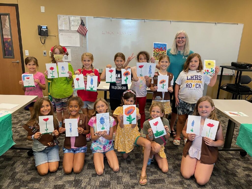 Children display flower paintings they made at a Williamson County Art Guild class