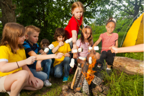 Kids roasting marshmallows around a campfire on a camping trip near Round Rock