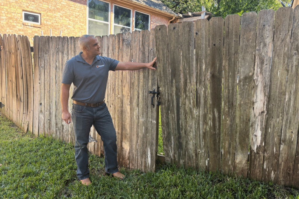 Ross Black inspecting a backyard wood fence during a home inspection