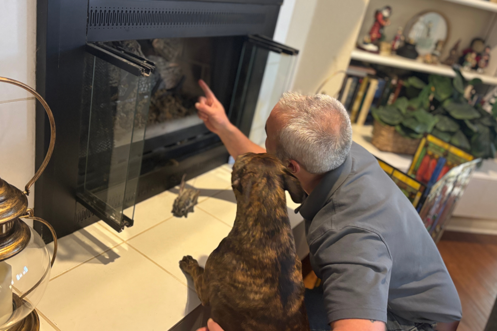 Ross Black inspecting a fireplace with one of the family's rescue dogs.
