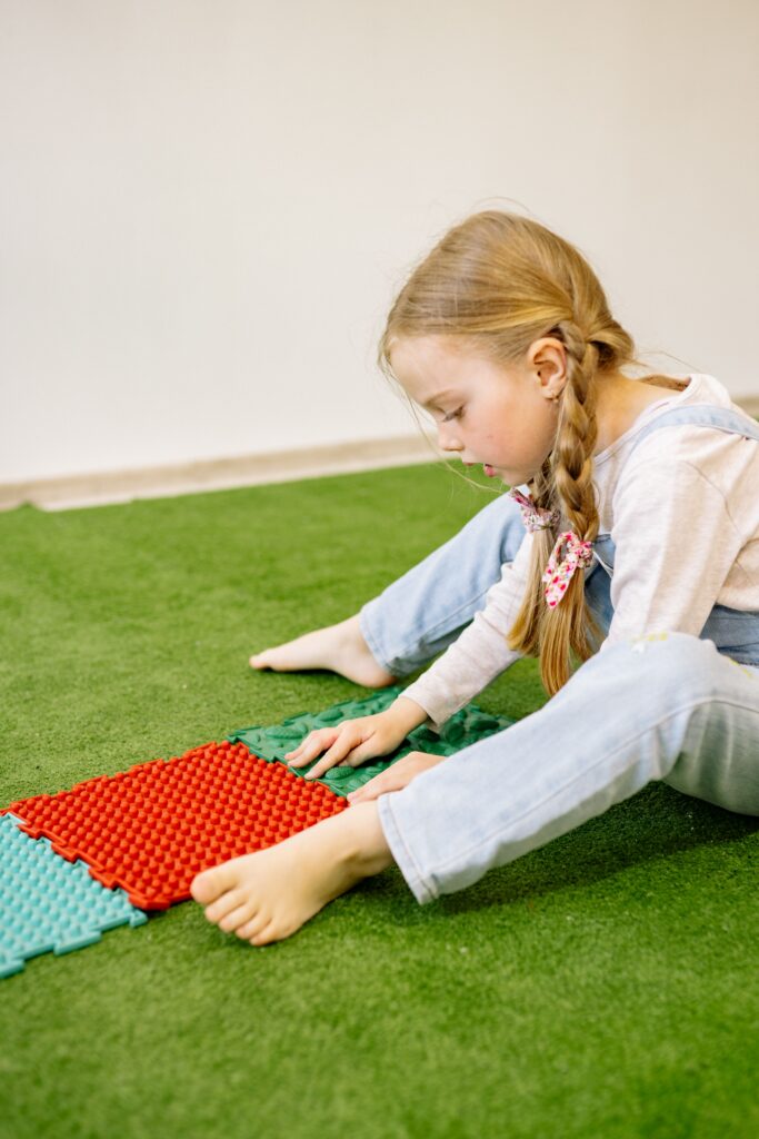 Child arranging colorful foam play tiles on the floor for indoor summer play