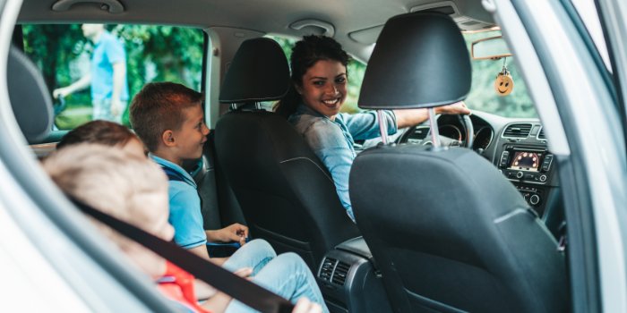 Mom and kids in the car ready for a summer outing with a car kit packed.